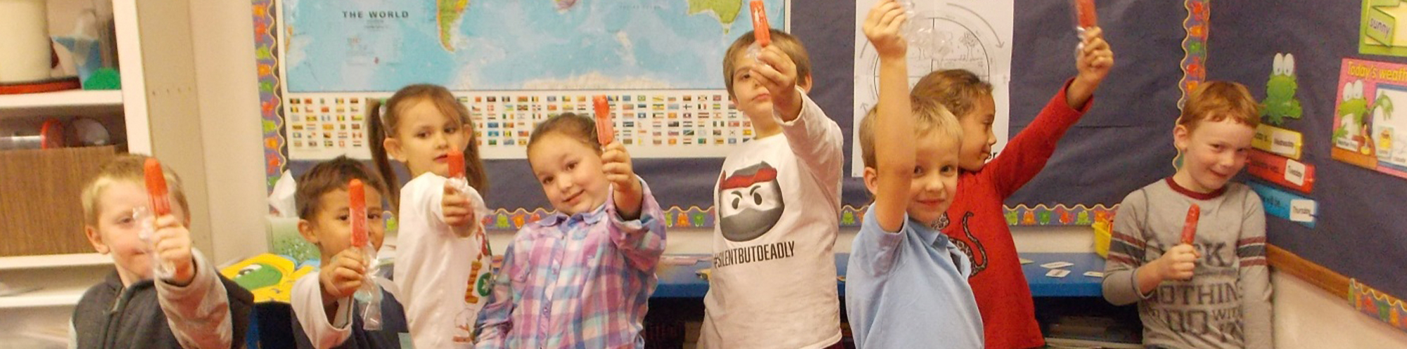 Young students holding up popsicles