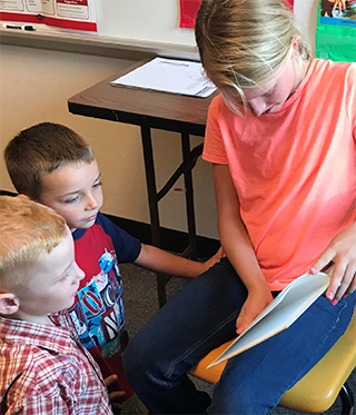 Girl reading to younger students