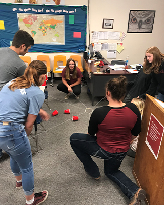 Students playing game with cups and string